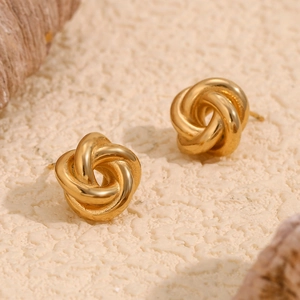 Detailed macro view of gold-plated twisted knot stud earrings on a natural stone base