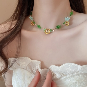 Detail of sunflower and bee necklace with yellow enamel and green beads on model
