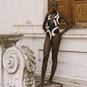 Detail of black and white geometric high-waist bikini against a classical stone wall