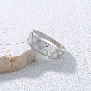 Macro detail of silver stainless steel ring with wave texture on natural stone