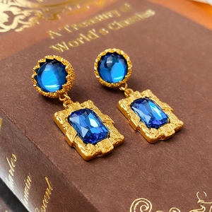 Vue macro de boucles d'oreilles dorées vintage avec cristaux bleus sur un livre