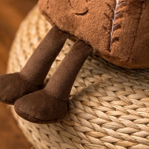 Close-up of soft brown plush toy legs and feet on a woven mat with warm lighting