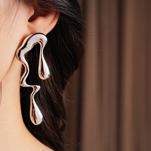 Gros plan d'une boucle d'oreille goutte en métal liquide argenté sur un mannequin poli