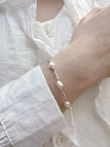 Detail of s925 silver bracelet with baroque freshwater pearls worn on a white shirt