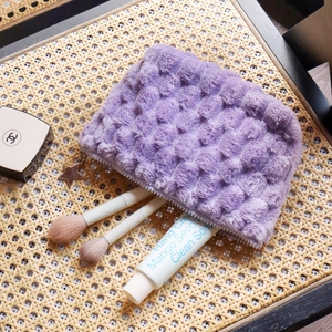 Soft purple plush checkered makeup bag with star charm zipper on woven background
