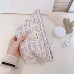 Detailed texture of purple and white tweed makeup bag with woven gold thread accents