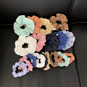 Colorful fabric scrunchies in various sizes and bright colors displayed on black leather