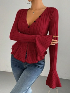 Detailed texture of burgundy ribbed knit top with V-neckline and ruffled hem detail