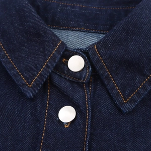 Détail du col en denim bleu foncé et boutons argentés avec surpiqûres orange contrastées