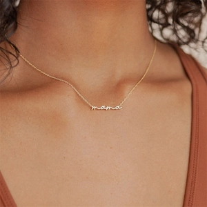 Close-up of a gold mama letter pendant necklace worn by a model for a warm look