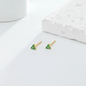 Close-up of minimalist gold triangle stud earrings with three green zircon stones