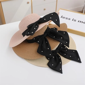 Women's straw sun hat with large black bow and pearl details in multiple colors