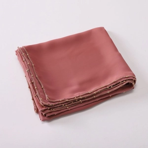Macro detail of rose pink chiffon scarf featuring delicate gold bead trim on the edges