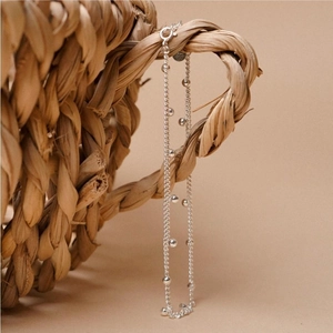 Minimalist S925 sterling silver beaded chain anklet hanging on a woven basket handle