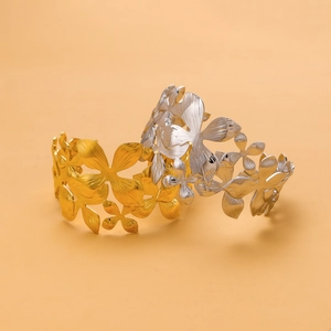 Detailed view of hollow flower pattern on gold and silver stainless steel open bangles