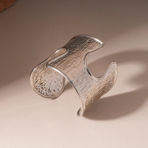 Close-up of a wide silver cuff bracelet featuring a textured hammered metal surface
