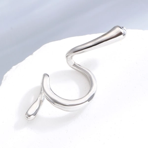 Macro shot of silver spiral ear cuff with metallic texture on white stone background