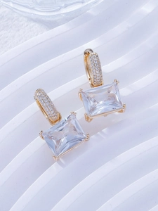 Detailed macro view of square zircon drop earrings with gold pavé setting and clear crystals