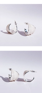 Macro shot of cream enamel C-shaped hoop earrings with silver-tone sculpted leaf design