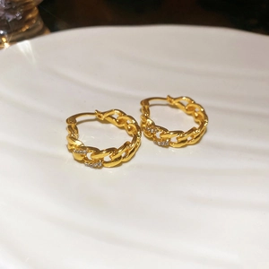 Macro shot of gold-plated chain link earrings featuring delicate pave-set diamonds