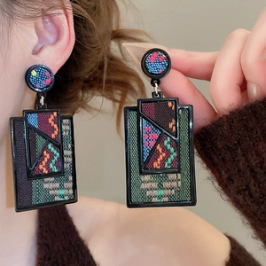 Detailed close-up of geometric acrylic earrings with bohemian woven fabric patterns