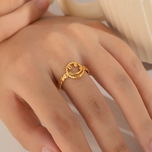 Close-up of gold stainless steel smiley face ring worn on the index finger by a model
