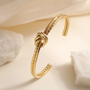 Minimalist gold knotted geometric open cuff bracelet with a polished metallic finish