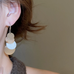 Detail of layered geometric acrylic tassel earrings worn by model for beach style