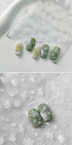 Detail of 5D white floral embossed nail stickers on Morandi green and cream nails
