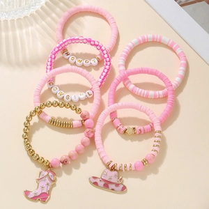 Detailed macro of pink clay beads and Western-themed charms with HOWDY lettering