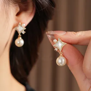 Elegant gold starburst pearl drop earrings with diamond inlay and white shell details