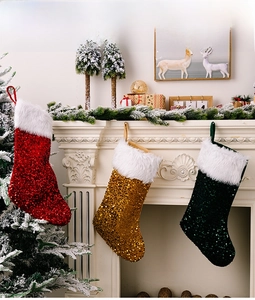 Trois chaussettes de Noël à paillettes rouge, or et vert suspendues à la cheminée