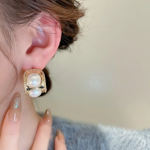 Détail de boucles d'oreilles vintage dorées en C avec double perle pour femme chic
