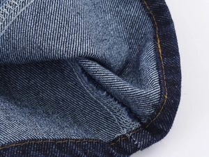 Gros plan sur le tissu denim bleu avec coutures orange contrastées et texture sergé