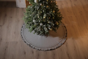 Detailed view of grey knitted Christmas tree skirt with festive patterns and tassel trim