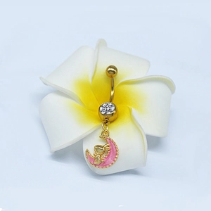 Dettaglio del piercing all'ombelico luna dorata con angelo rosa e zircone su un fiore di plumeria