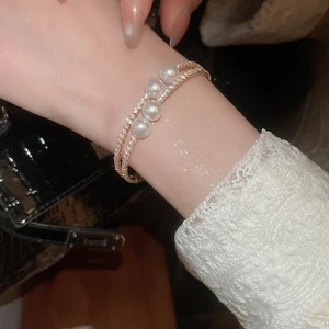 Gros plan d'un bracelet double couche en or serti de zircons et orné de quatre perles