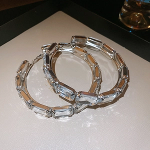 Detail of silver hoop earrings with clear baguette-cut crystals on a leather tray