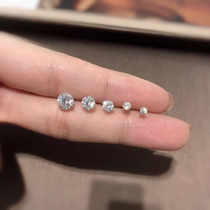 Five round cubic zirconia stud earrings in varying sizes shown on a fingertip