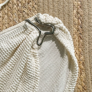 Close-up of white seersucker bikini fabric with a stylish silver wavy metal buckle