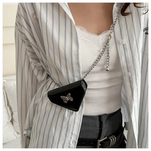 Detail of a black triangle mini bag with silver butterfly charm and metal chain strap