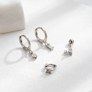 Detailed view of four silver piercing earrings with cubic zirconia charms and drops