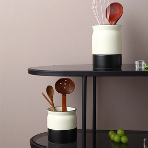 Modern black and white ceramic cutlery holder set with wooden utensils in a kitchen shelf