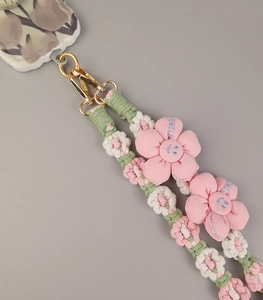 Detail of handmade woven phone lanyard featuring pink fabric flowers and gold lobster clasp