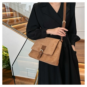 Detail view of brown frosted suede crossbody bag with leather strap on black dress