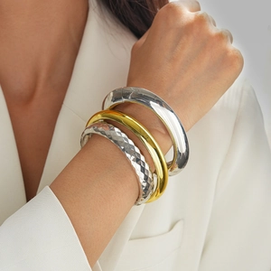 Close-up of gold and silver chunky metal bangles with smooth and geometric textures