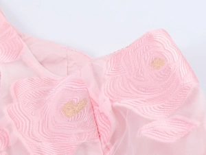 Gros plan sur tissu en tulle rose avec broderie de roses et détails de cœurs dorés