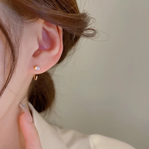 Minimalist gold zircon circle hoop earrings worn on ear with elegant geometric design