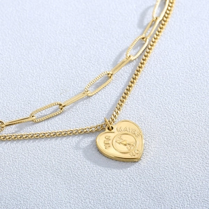 Detail of gold double-layer necklace featuring heart pendant with spinning yes-no arrow