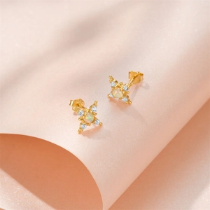 Close-up of gold starburst stud earrings featuring white opal and diamond accents
